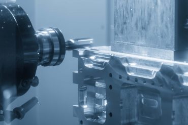 The horizontal CNC milling machine cutting the aluminum automotive parts by solid flat nose end mill tool in the light blue scene. The automotive parts manufacturing process by CNC milling machine.